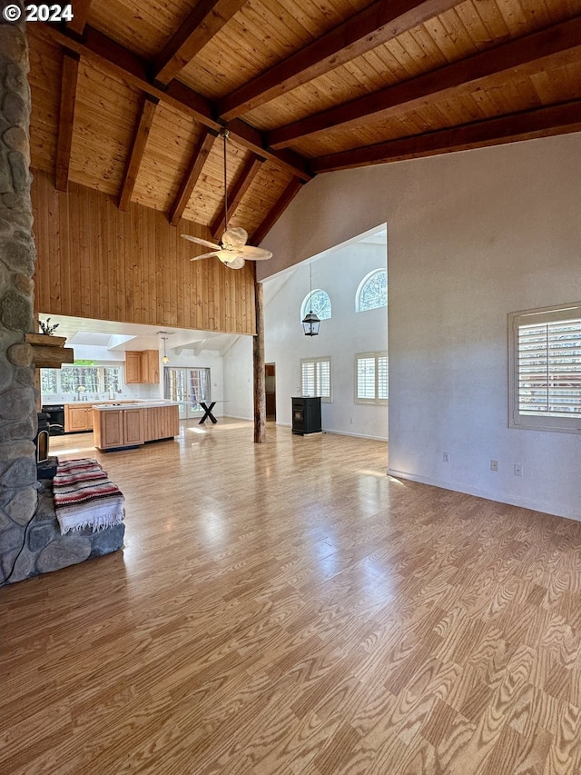 unfurnished living room featuring wooden ceiling, high vaulted ceiling, ceiling fan, light wood-type flooring, and beam ceiling