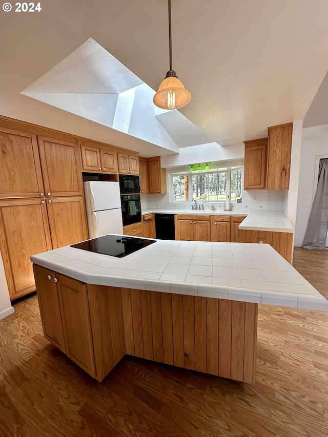 kitchen with kitchen peninsula, tasteful backsplash, tile counters, and black appliances