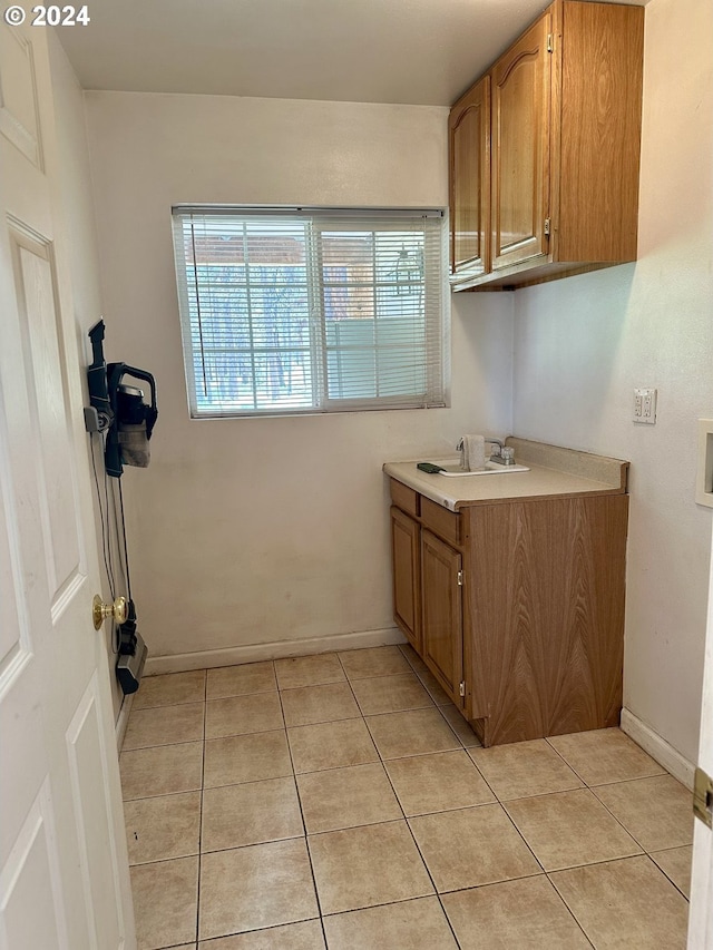 laundry room with cabinets, light tile patterned floors, hookup for a washing machine, and sink