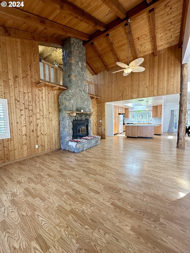 unfurnished living room with ceiling fan, high vaulted ceiling, wooden ceiling, beamed ceiling, and a wood stove