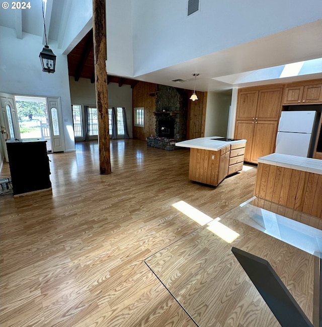 kitchen with a kitchen island, a towering ceiling, beamed ceiling, decorative light fixtures, and white fridge