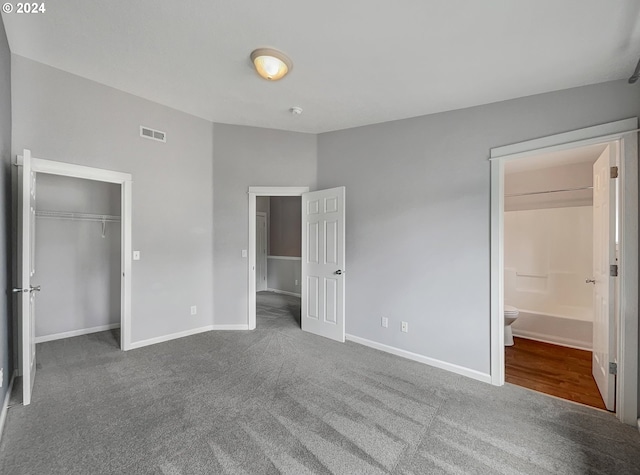 unfurnished bedroom with a closet, carpet flooring, and ensuite bath