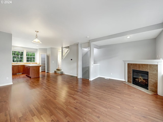 unfurnished living room featuring a tile fireplace and hardwood / wood-style flooring