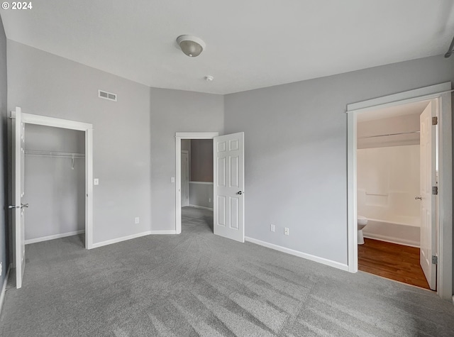 unfurnished bedroom with ensuite bath, hardwood / wood-style flooring, and a closet