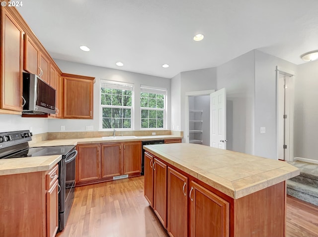 kitchen with a center island, sink, dishwashing machine, range with electric stovetop, and light hardwood / wood-style flooring