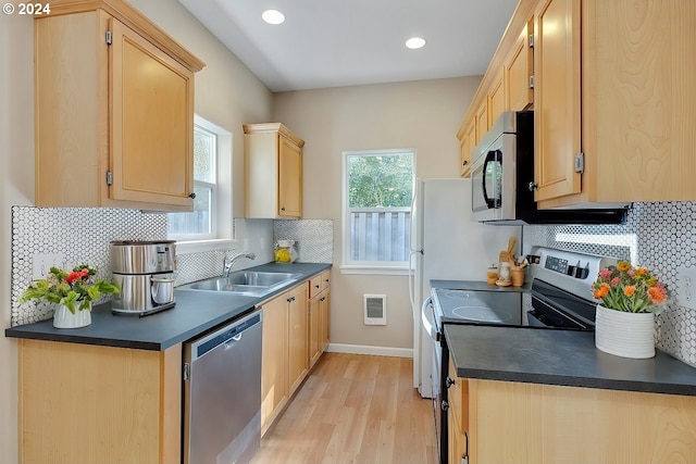 kitchen featuring sink, decorative backsplash, light brown cabinetry, appliances with stainless steel finishes, and light hardwood / wood-style floors