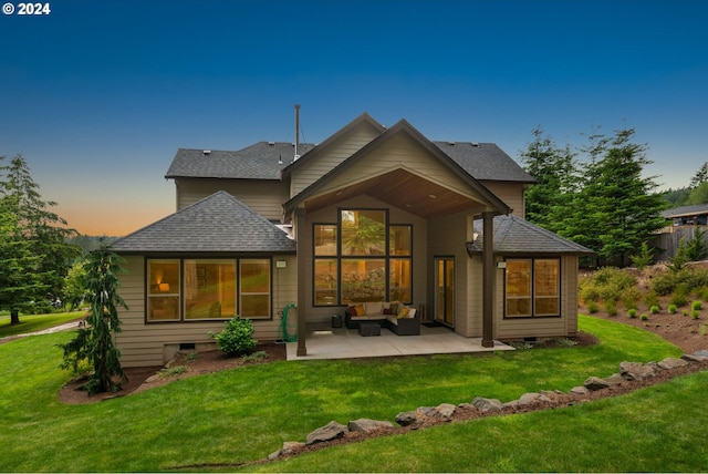 back house at dusk with an outdoor hangout area, a patio area, and a lawn