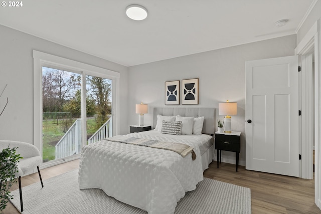 bedroom featuring light hardwood / wood-style floors, access to exterior, and ornamental molding