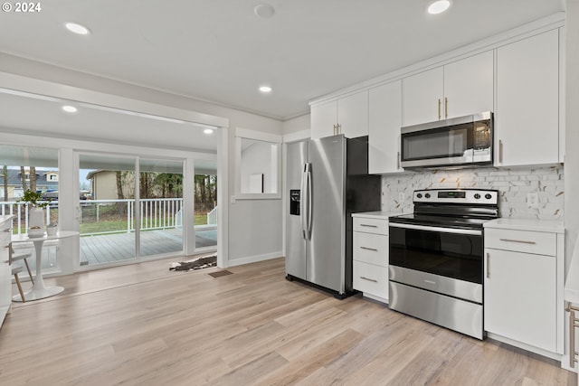 kitchen with tasteful backsplash, white cabinetry, stainless steel appliances, and light hardwood / wood-style flooring