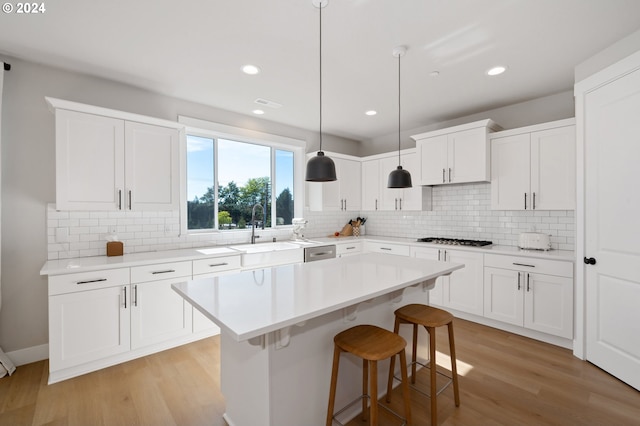 kitchen featuring decorative backsplash, light hardwood / wood-style floors, white cabinetry, hanging light fixtures, and a kitchen island