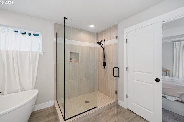 bathroom featuring plus walk in shower and hardwood / wood-style floors