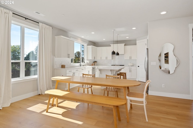 dining space with sink, light hardwood / wood-style floors, and a healthy amount of sunlight