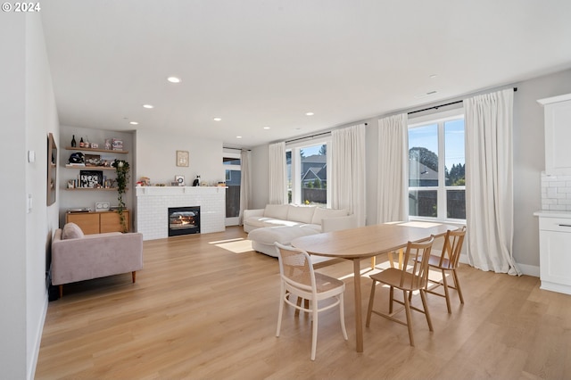 dining area with light wood-type flooring and a fireplace