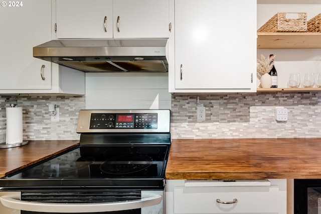 kitchen featuring range hood, tasteful backsplash, black stove, and white cabinets