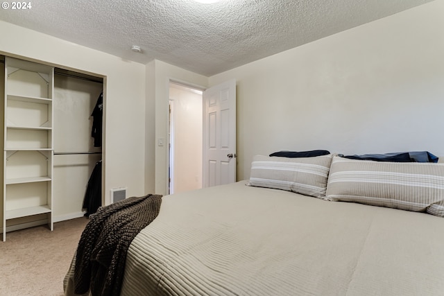 carpeted bedroom with a textured ceiling and a closet