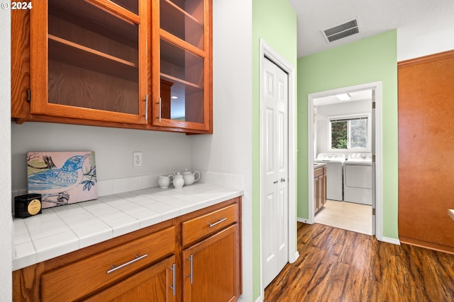 interior space featuring tile countertops, washing machine and clothes dryer, and dark wood-type flooring