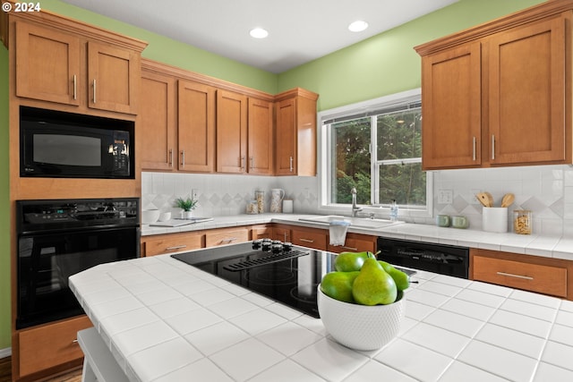 kitchen with sink, tile counters, tasteful backsplash, and black appliances