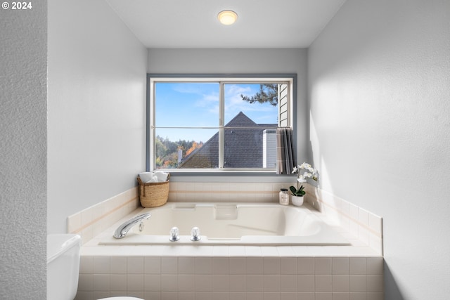 bathroom featuring a relaxing tiled tub and toilet