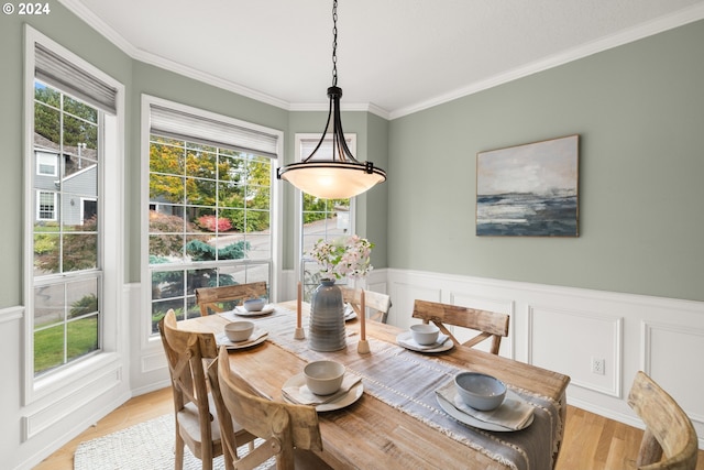 dining space with ornamental molding and light hardwood / wood-style flooring