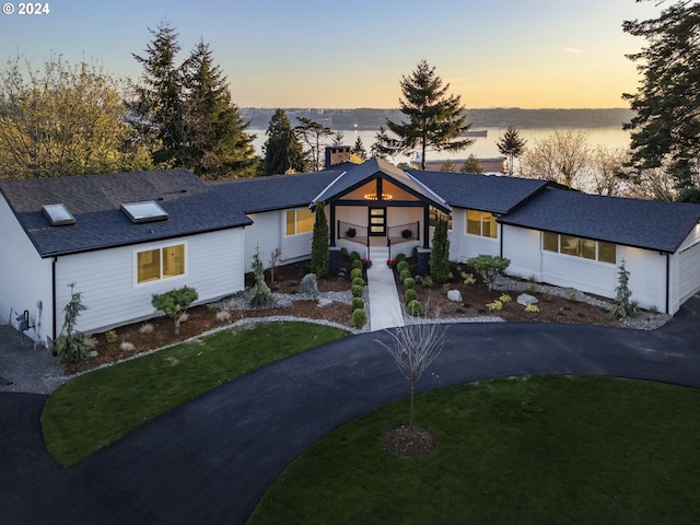 view of front of property featuring a front lawn, driveway, and a shingled roof