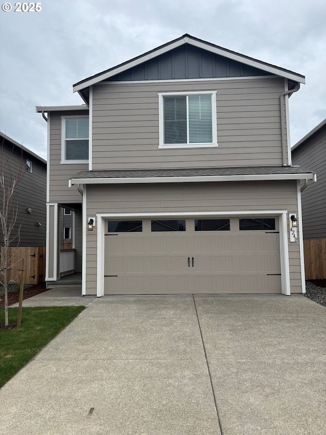 traditional-style home with a garage, board and batten siding, concrete driveway, and fence