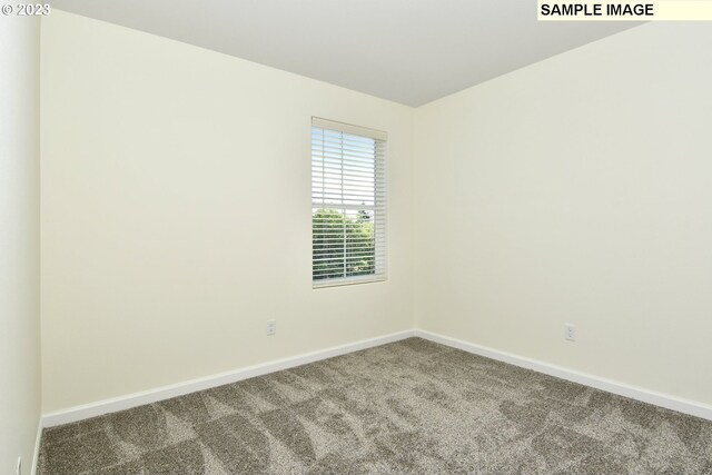 carpeted spare room featuring baseboards