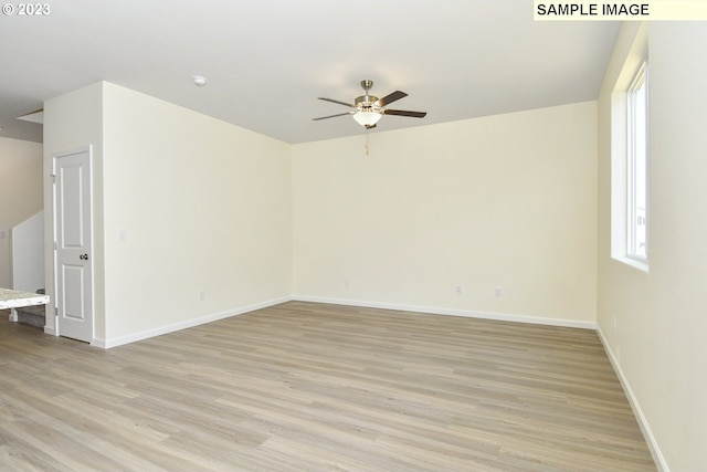 spare room with light wood-style flooring, a ceiling fan, and baseboards