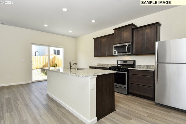 kitchen with an island with sink, recessed lighting, dark brown cabinetry, appliances with stainless steel finishes, and light wood-type flooring