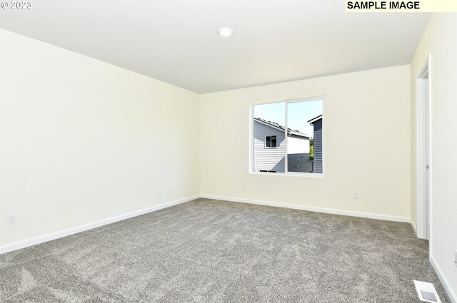 unfurnished room featuring carpet, visible vents, and baseboards