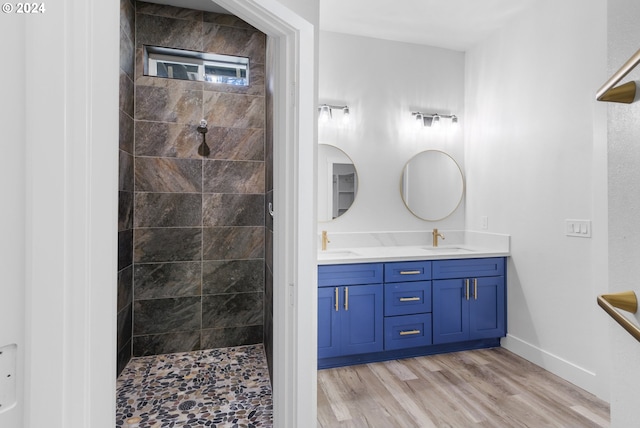 bathroom featuring a tile shower, wood-type flooring, and dual bowl vanity