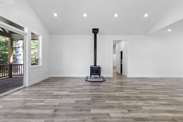 unfurnished living room featuring lofted ceiling, a wood stove, and light hardwood / wood-style flooring