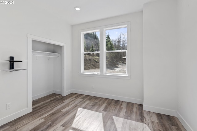 unfurnished bedroom with a closet, multiple windows, and light hardwood / wood-style flooring