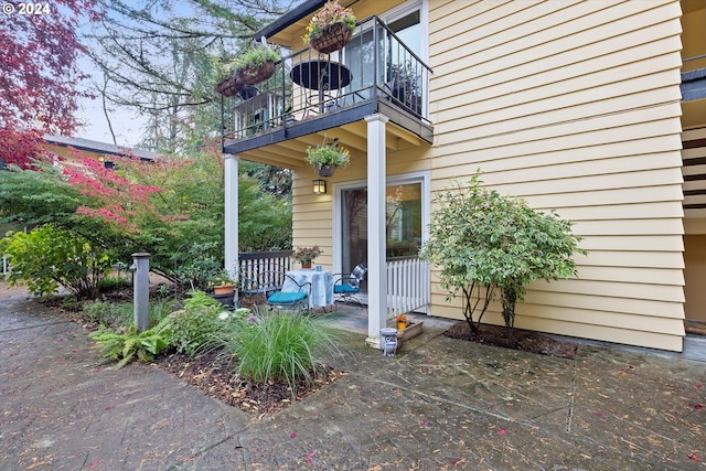 view of exterior entry with a balcony and a patio area