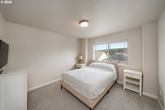 bedroom featuring light carpet and a textured ceiling