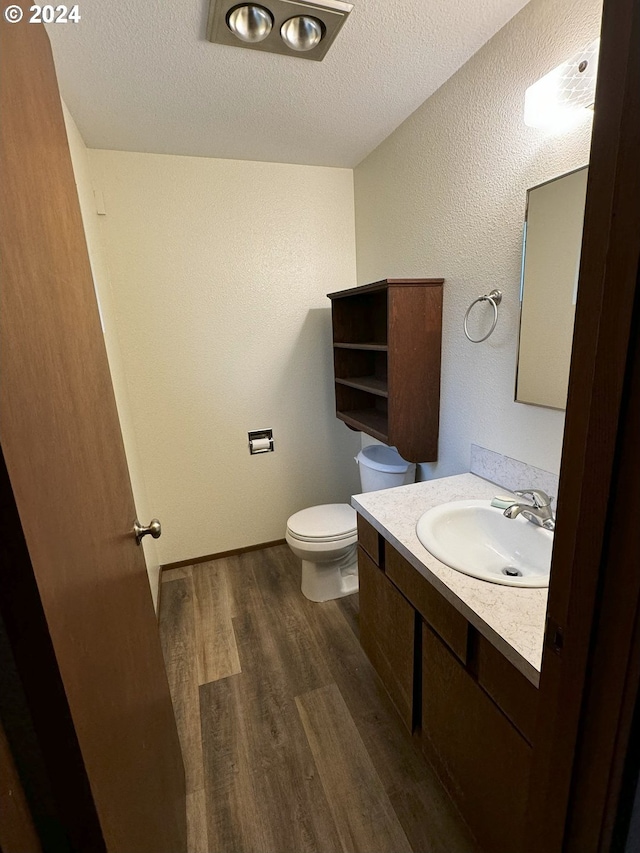 bathroom with vanity, a textured ceiling, hardwood / wood-style flooring, and toilet