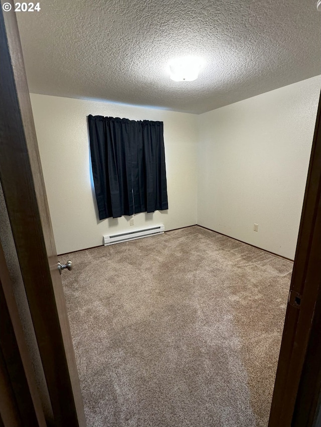 spare room with carpet, a textured ceiling, and a baseboard heating unit