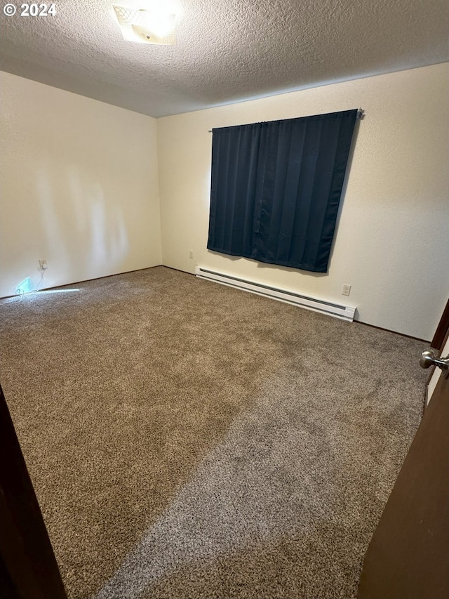 empty room featuring carpet flooring, a textured ceiling, and a baseboard heating unit