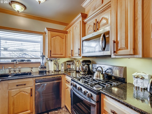 kitchen with appliances with stainless steel finishes, ornamental molding, dark stone counters, and sink