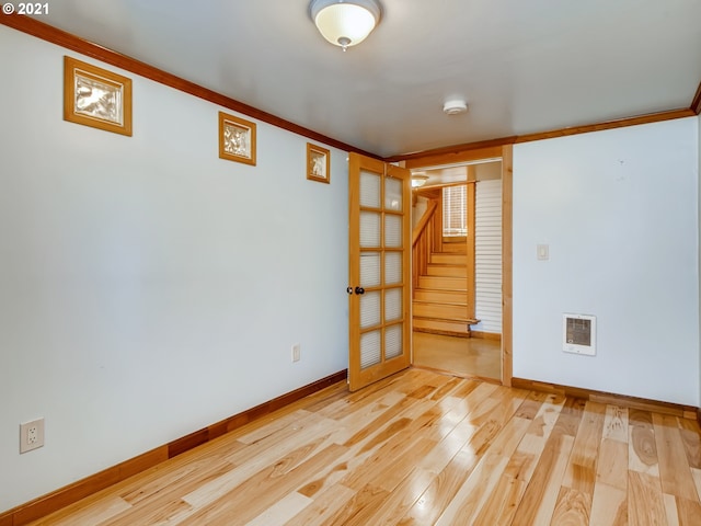 spare room with heating unit, crown molding, and light hardwood / wood-style flooring