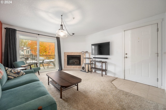 living room with a tiled fireplace, light carpet, and a textured ceiling