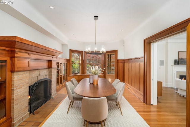 dining space with a fireplace, light hardwood / wood-style floors, and a chandelier