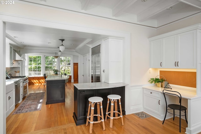 kitchen featuring white cabinets, wall chimney range hood, and a kitchen breakfast bar