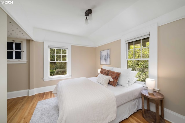 bedroom with lofted ceiling, light hardwood / wood-style floors, and multiple windows