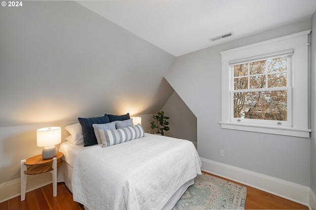 bedroom with hardwood / wood-style floors and lofted ceiling