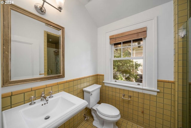 bathroom with tile walls, toilet, lofted ceiling, sink, and tile floors