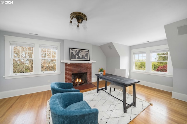 living area with light hardwood / wood-style floors and a brick fireplace