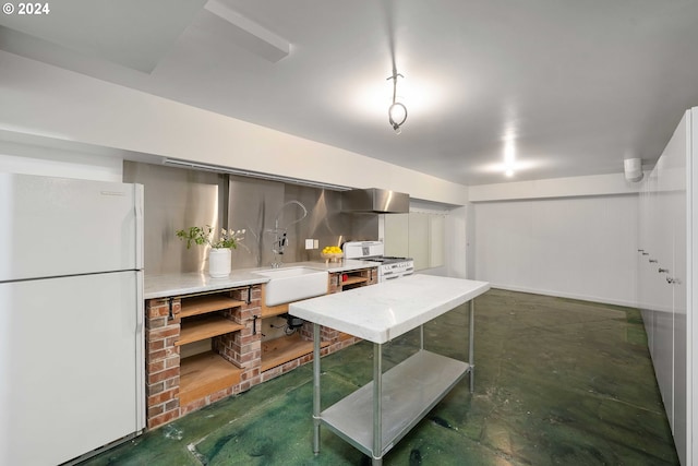 basement featuring white refrigerator and sink