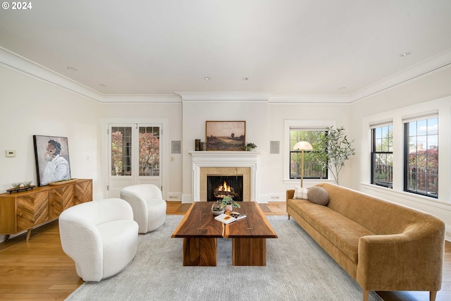 living room with light hardwood / wood-style floors, a tile fireplace, and crown molding