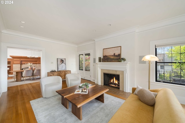 living room with a wealth of natural light, crown molding, and a tiled fireplace