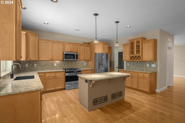 kitchen featuring stainless steel appliances, a center island, light hardwood / wood-style flooring, light stone countertops, and sink